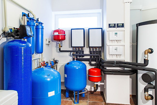 well water system blue and red tanks on walls with pipes to water heater